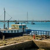 A boat docked at a pier with many boats in the distance