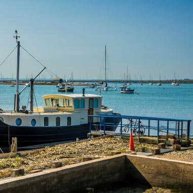 A boat docked at a pier with many boats in the distance