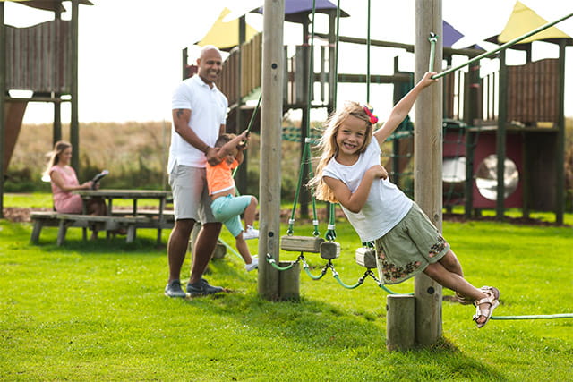 A family playing on the outdoor adventure playground at Coopers Beach Holiday Park
