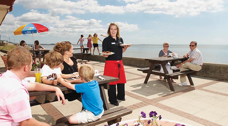 Families enjoying food and drinks on the outdoor patio with a sea view