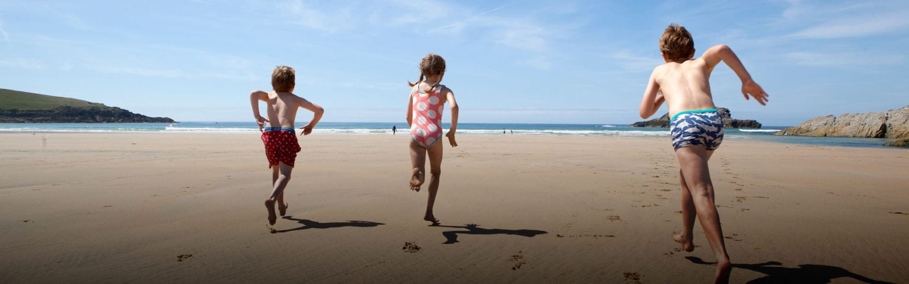 Three children running on a beach