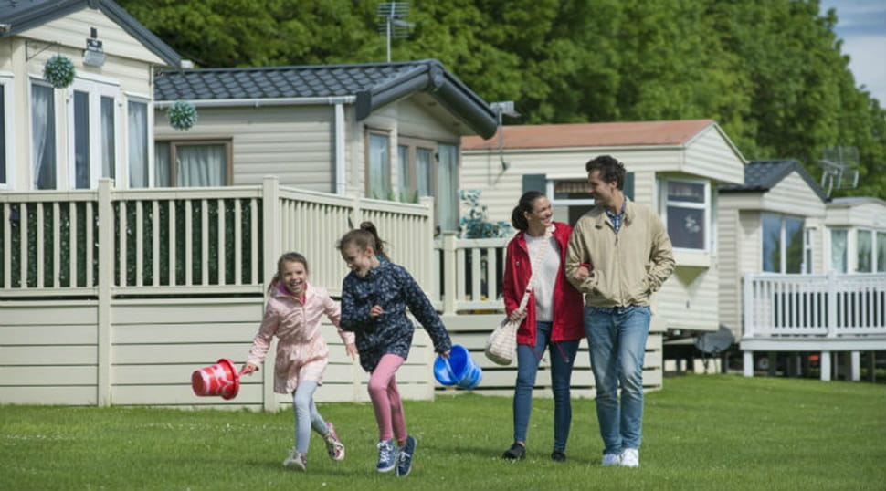 A family walking by the accommodation with buckets and spades at Cresswell Towers Holiday Park