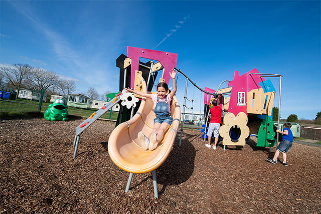 A girl on the slide on the outdoor adventure playground at Cresswell Towers Holiday Park
