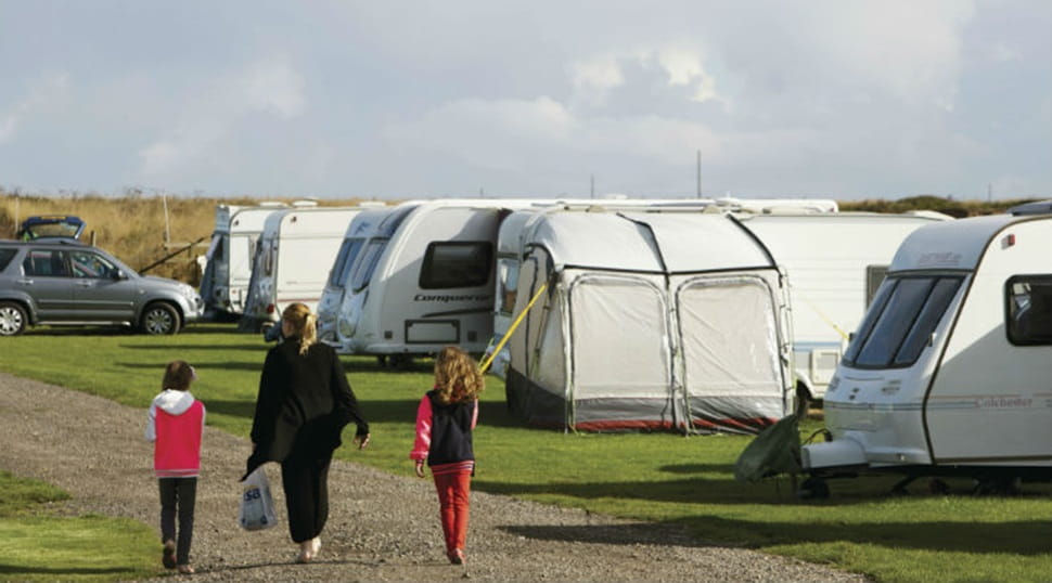 A family walking through the touring caravan pitches at Crimdon Dene Holiday Park