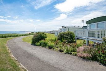 Paved road next to a caravan holiday park by the sea