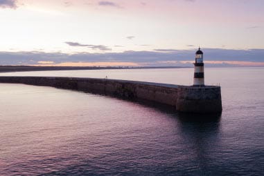 Pier stretching out into the sea with a traditional lighthouse 