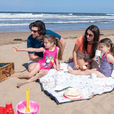 Family picnicing on a blanket on the beach