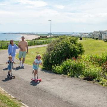 Children on roller skates with parents on a footpath