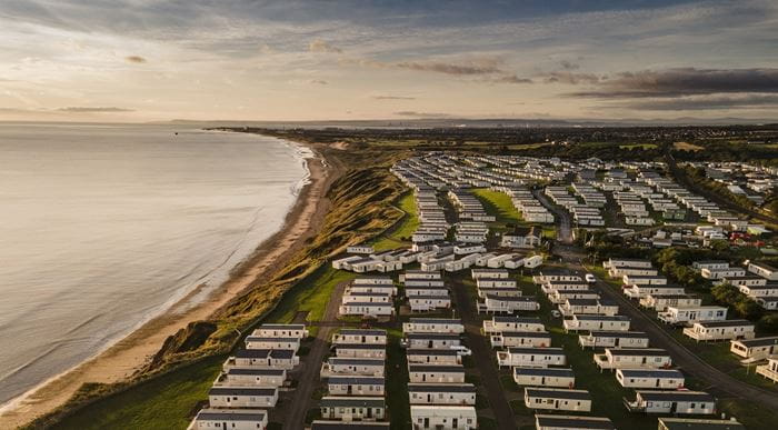 An aerial view of Crimdon Dene Holiday Park and the coastline stretching into the distance at sunset