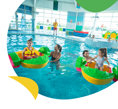 A family playing on Aqua Paddlers in the indoor swimming pool at Crimdon Dene Holiday Park