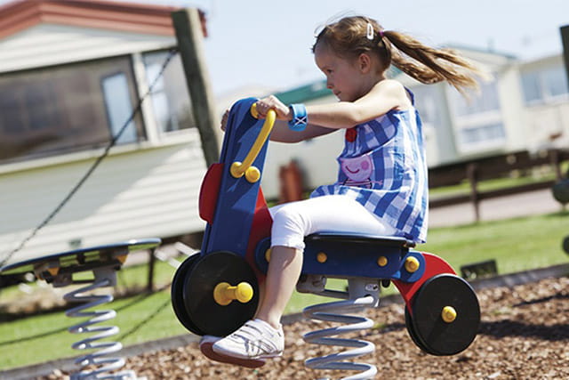 A child riding a rocker on the adventure playground at Eyemouth Holiday Park