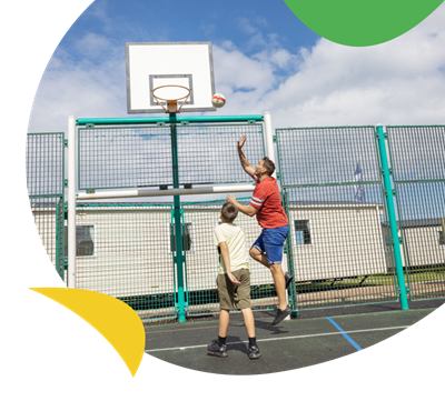 Father and son playing basketball on the multi-sports court at Eyemouth Holiday Park