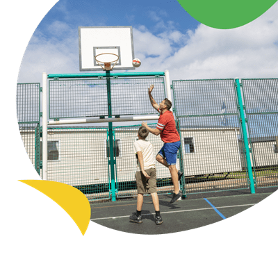 Father and son playing basketball on the multi-sports court at Eyemouth Holiday Park