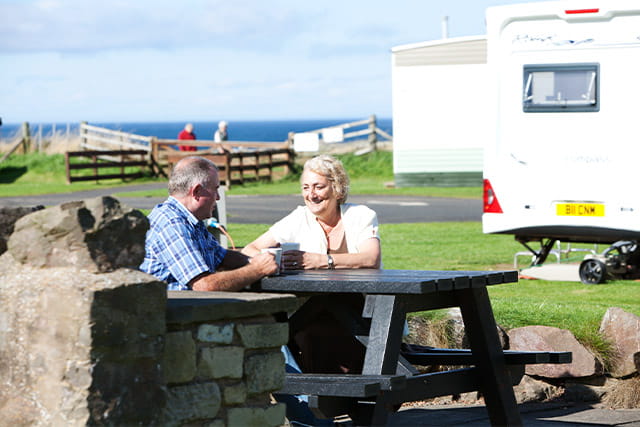A couple sat outside their touring caravan