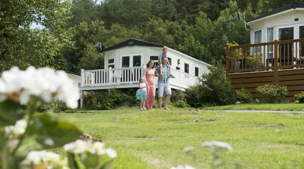 People walkling across the grass by the lodges at Fallbarrow Holiday Park