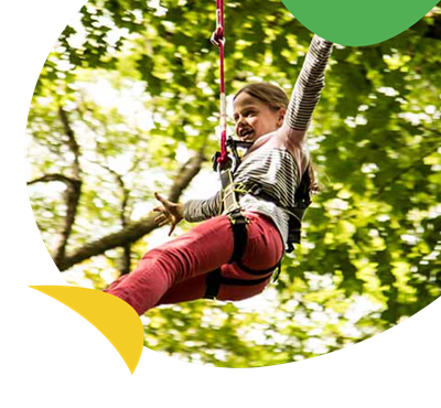 A girl swinging through the trees at the Treetop Trek atttraction