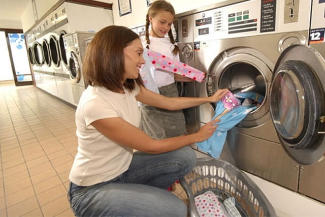 A mother and daughter unloading the washing machine at the launderette