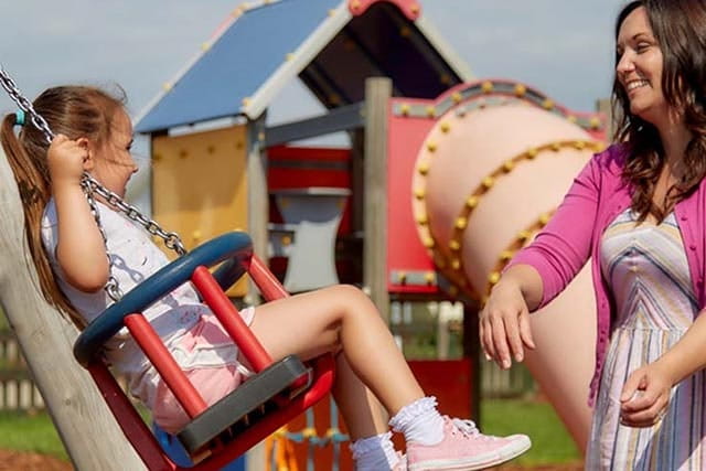 mother pushing young girl on a swing