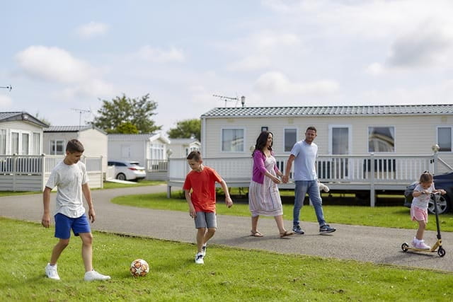 Family walk along road outside park homes at Heacham Beach Holiday Park
