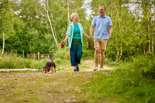 a couple walking through a woods with a dog