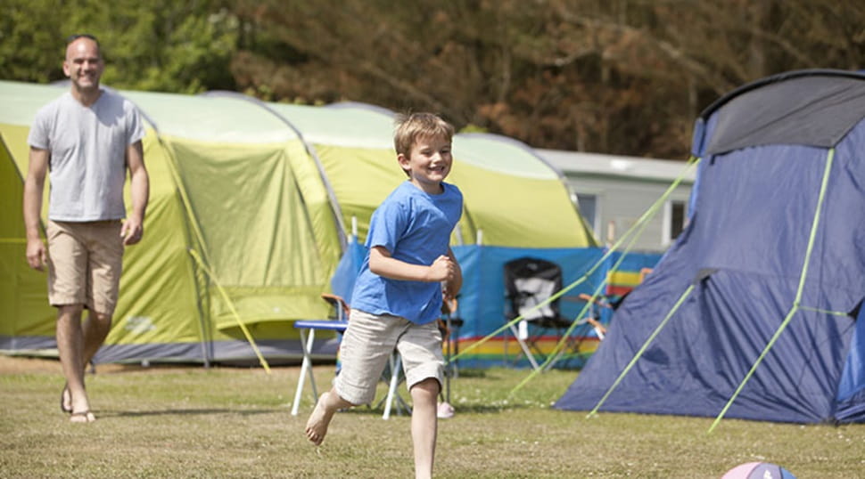 boy running past camping tents