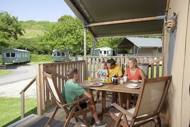 A family eating al fresco on their glamping tent veranda at Holywell bay Holiday Park