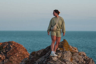 a woman stood on a rock by the coast