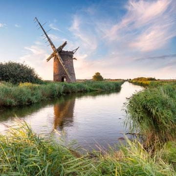 A still stream reflecting a mill in the background