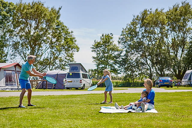 family playing tennis on the camping field
