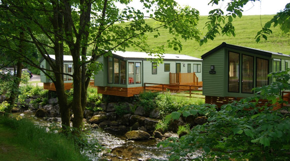 Lodges by the stream at Limefitt Holiday Park