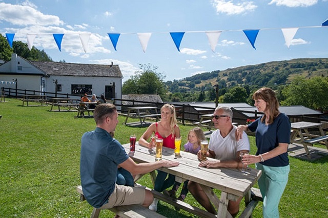 A family enjoying drinks in the sunny beer garden at Limefitt Holiday Park