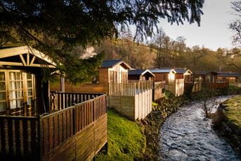 a river running past wooden lodge accommodation 