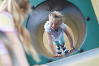 child playing in an adventure playground tunnel