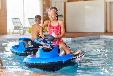 children on inflatable jet skis in an indoor pool