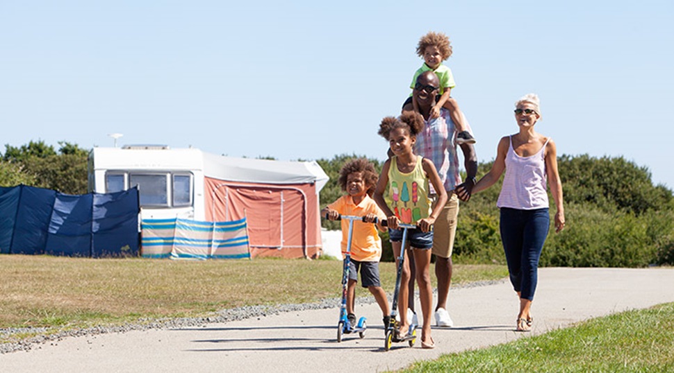 family walking down a path on a camp site with kids on scooters