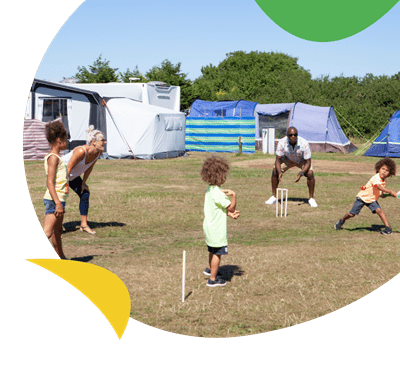 A family playing cricket on the camping field at Lizard Point Holiday Park