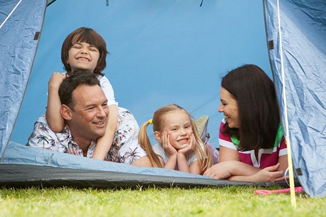 A family lying down and looking out of their tent at Lizard Point Holiday Park