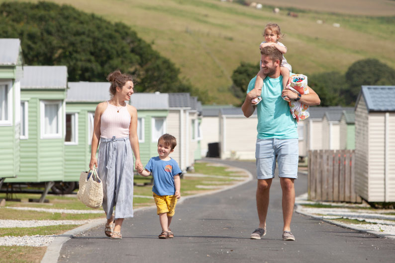 family walking down a path at a holiday park, the father has his toddler on his shoulders
