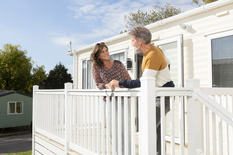 couple talking outside a caravan on its veranda