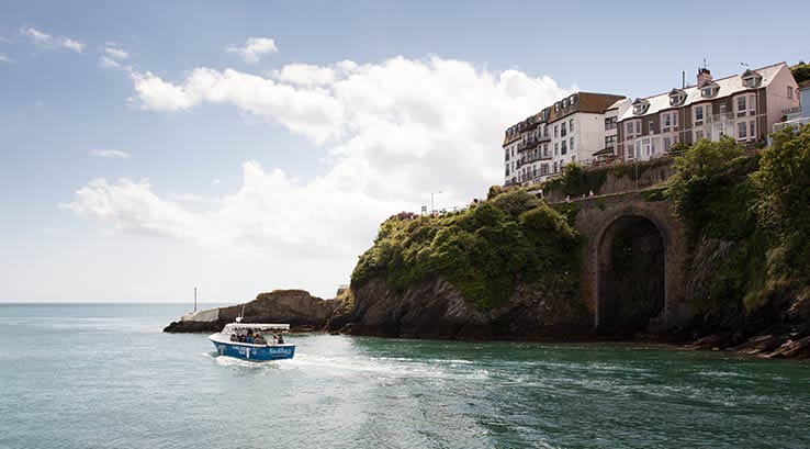boat passing cliffs at Looe Bay harbour