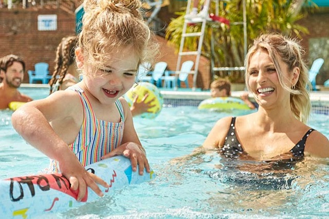 A mother and daughter splashing in the outdoor pool