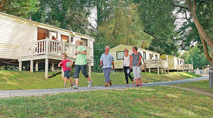 A family walking down a grassy hill from the caravans at Lower Hyde Holiday Park
