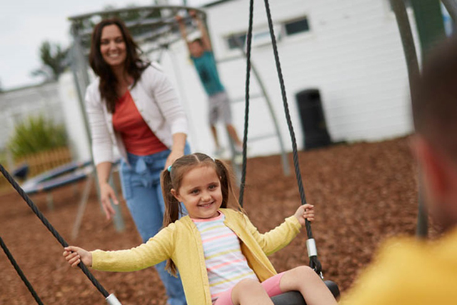 mother pushing daughter on a swing