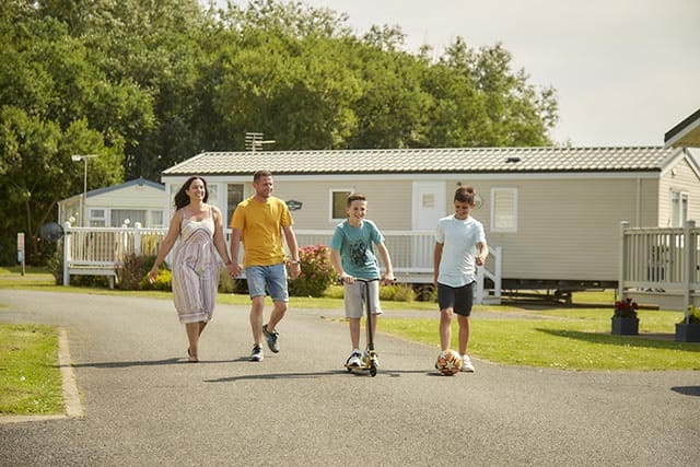 Family walking on road in front of park homes at Manor Park Holiday Park