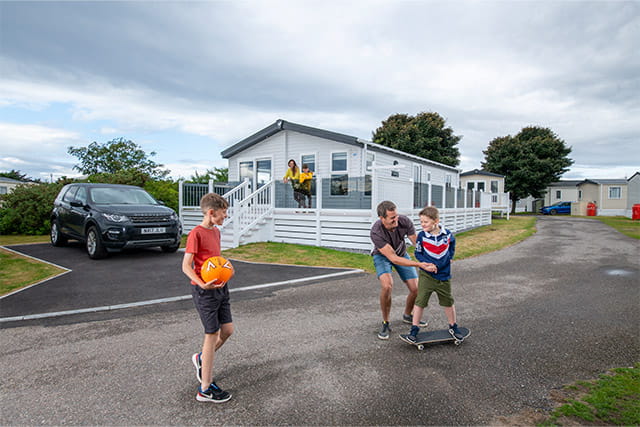 A family playing in front of their holiday caravan at Nairn Lochloy Holiday Park