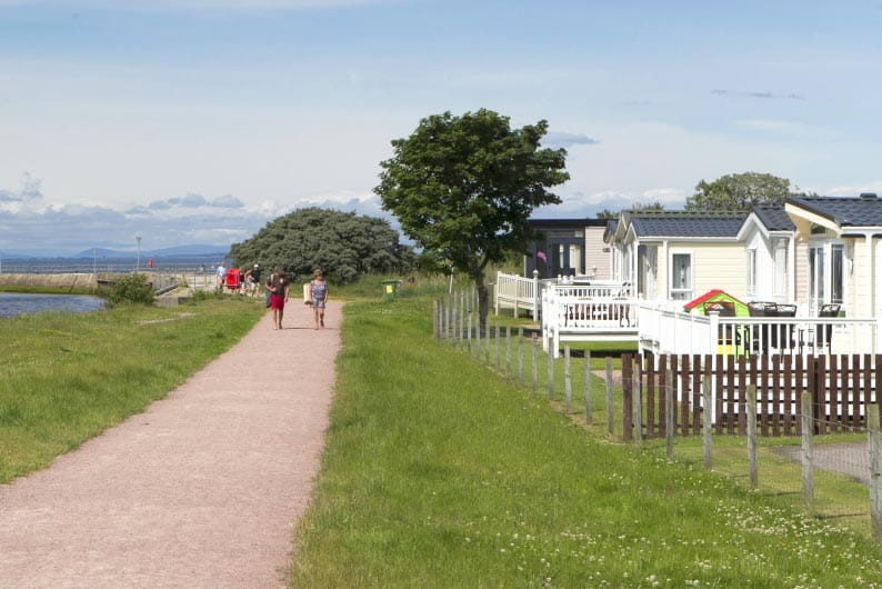 Couple walking down a path next to a caravan holiday park