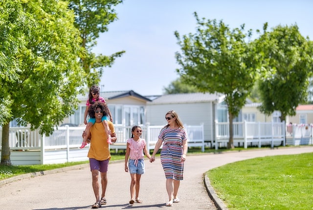 A family walking past holiday accommodation at Naze Marine Holiday Park