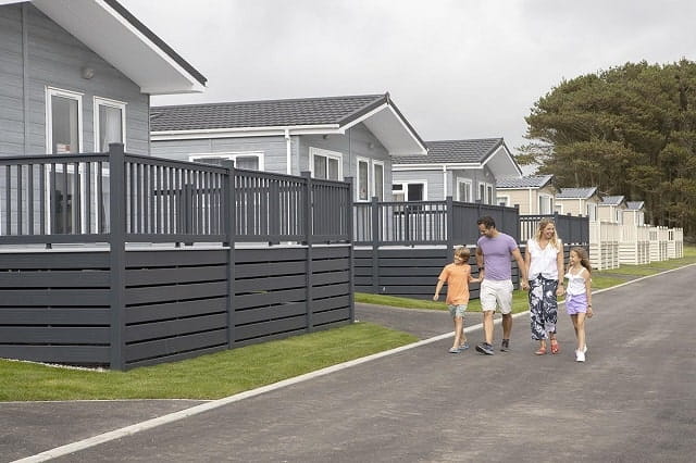 A family walking past a row of holiday lodges at Newquay Holiday Park
