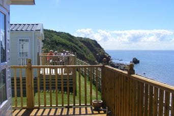 Wooden terrace view looking out at green hills and the sea