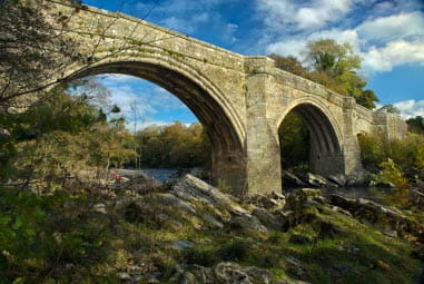 Stony historic bridge nestled in trees